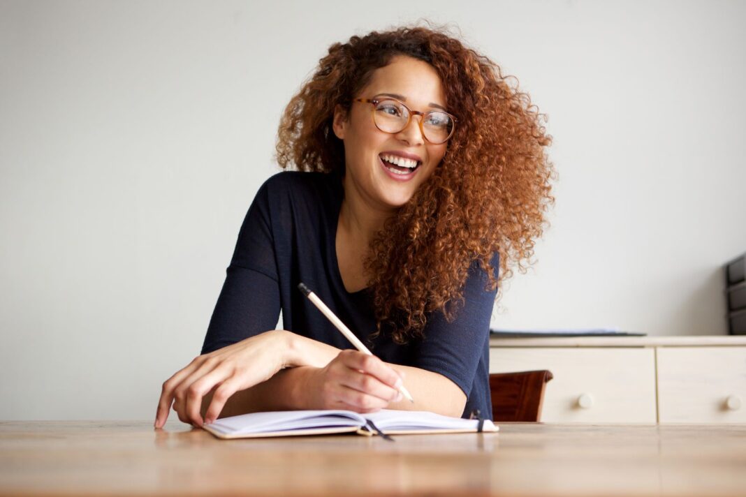 Femme qui est heureuse de rédiger une lettre de motivation pour être aide maternelle