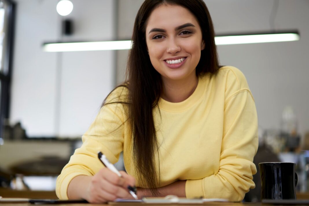Femme heureuse de rédiger une lettre de motivation pour une alternance gestion de la PME